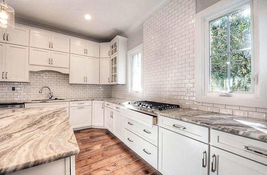 Kitchen with wavy tile backsplash and white cabinets with quartz countertops