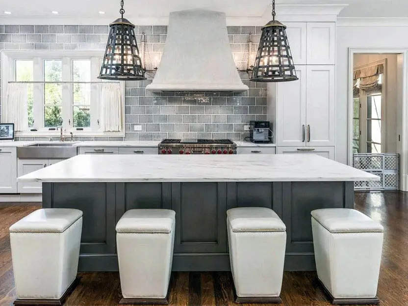 Kitchen with lamp style pendant lights, white uphostered stools and grey tiles
