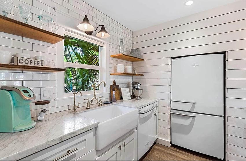Kitchen with shiplap walls with sunken refrigerator, white cabinets and white subway tile backsplash