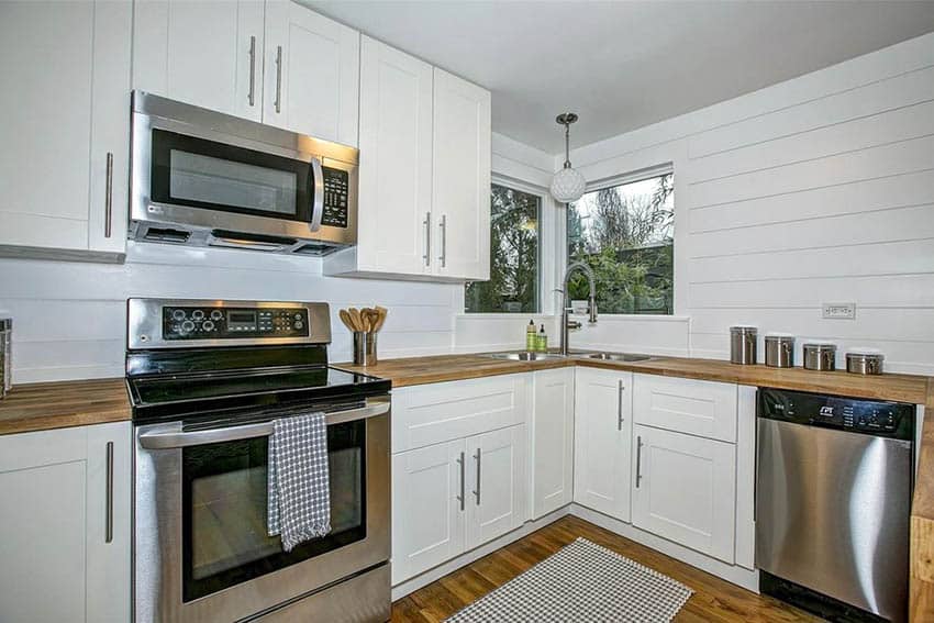 Kitchen with walls that use shiplap-look panels, cabinets in white and wood countertops