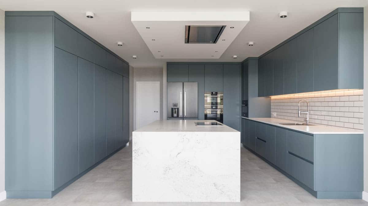 Sleek slate blue handleless cabinets with white quartz waterfall island