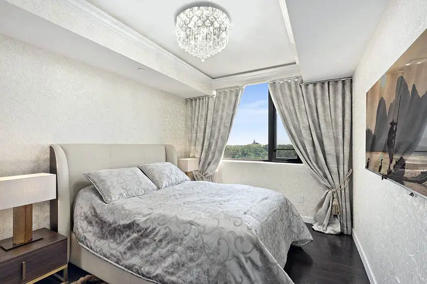 Bedroom with tray ceiling with crown molding and chandelier