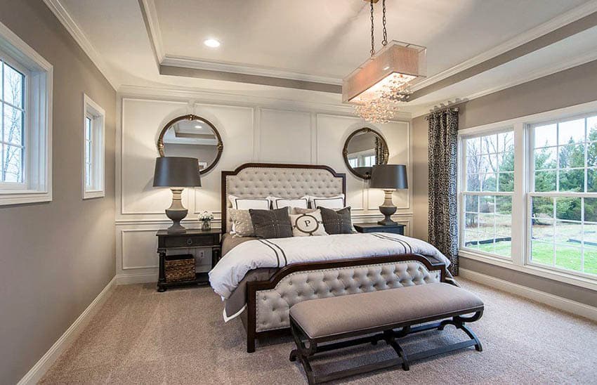 Contemporary bedroom with linear chandelier wall paneling tray ceiling and tufted bed