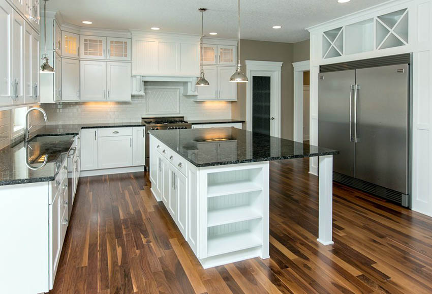 Country kitchen with white cabinets, black granite countertops and walnut flooring