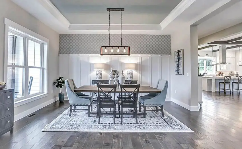 Dining room with gray tray ceiling and wood flooring and white wall paneling