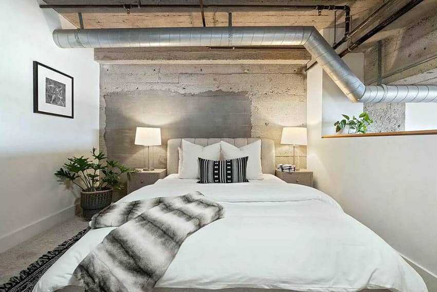 Industrial loft bedroom with exposed concrete ceiling and ductwork