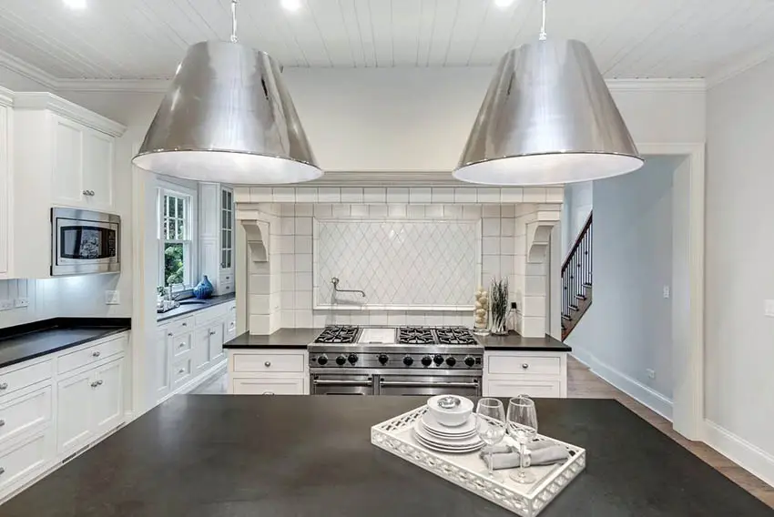 Kitchen with black soapstone countertop island and white cabinets with white shiplap ceiling
