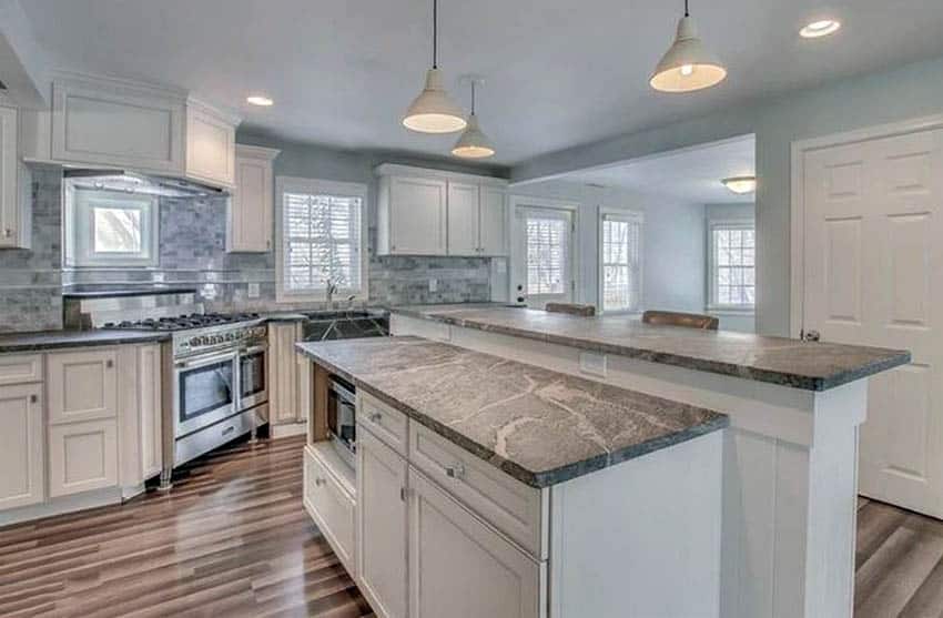Kitchen with gray soapstone breakfast bar island and countertops with white cabinets