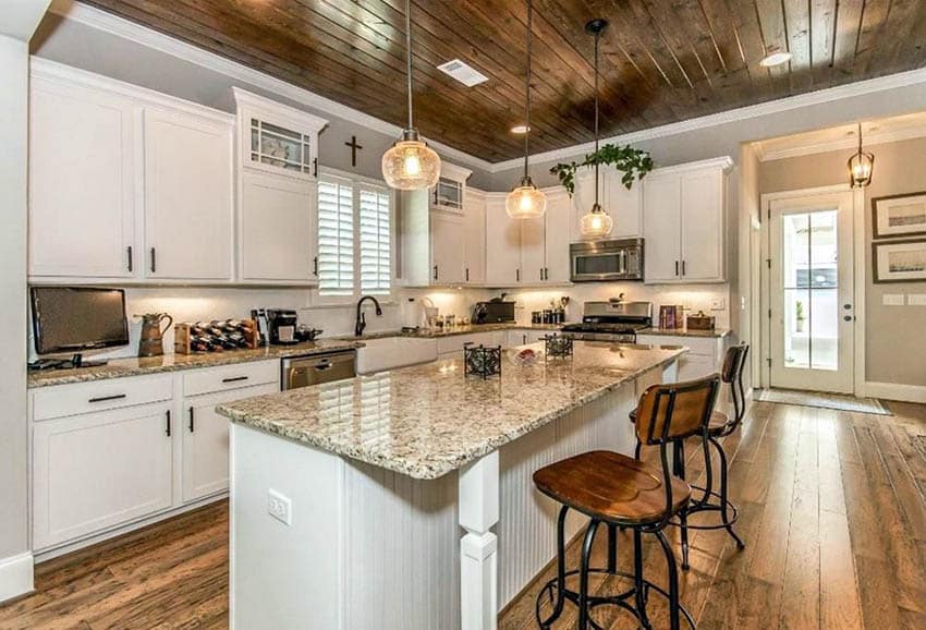 Kitchen with white cabinets and beadboard island beige granite countertops and shiplap ceiling