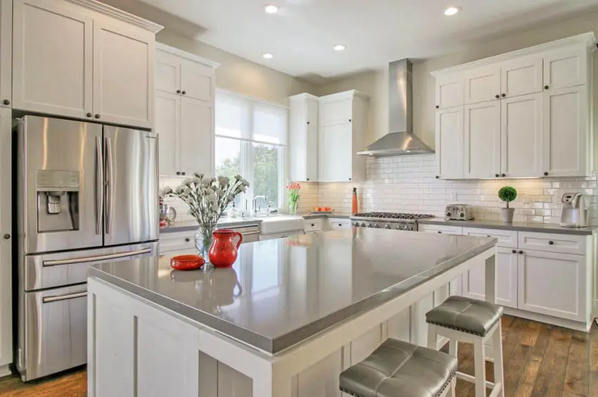 Kitchen with white cabinets and gray quartz countertops white tile backsplash and wood flooring