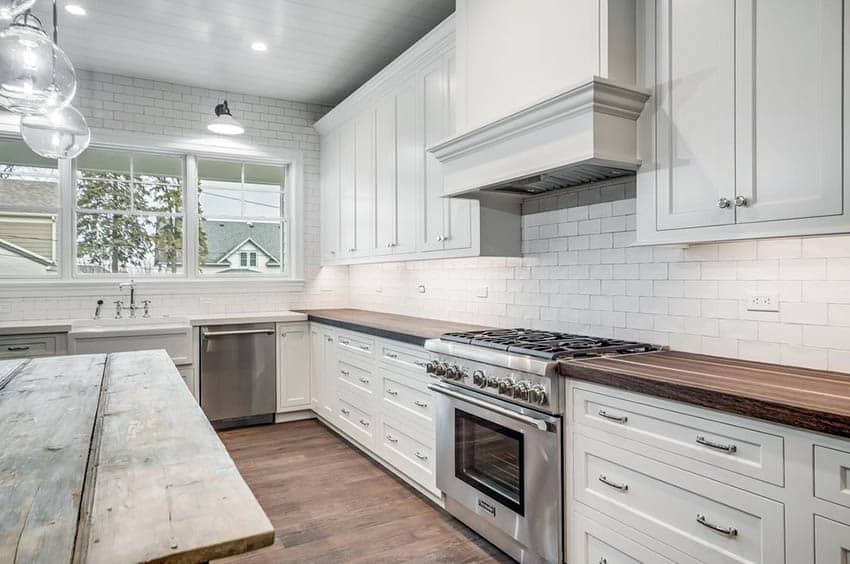 Kitchen with white cabinets and wood countertops and subway tile wall