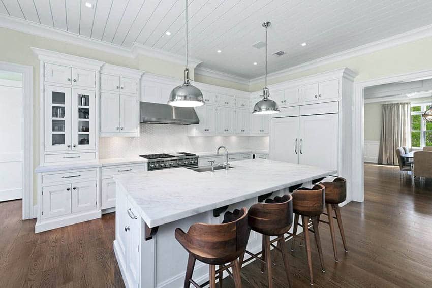 Kitchen with white cabinets, white marble countertops, tile backsplash and wood flooring