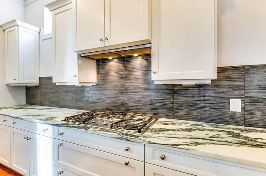 Kitchen with white cabinets with bold white and green marble countertops