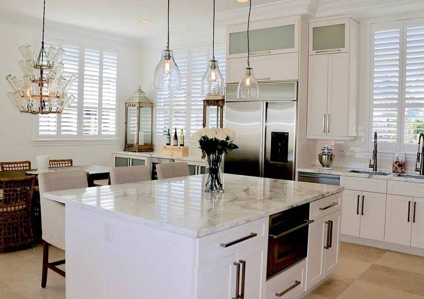 Kitchen with white soapstone countertops white cabinets and travertine flooring