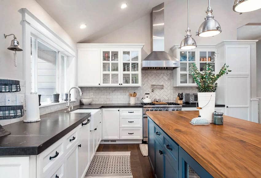 L shaped kitchen with black soapstone countertops, wood countertop island and white cabinets