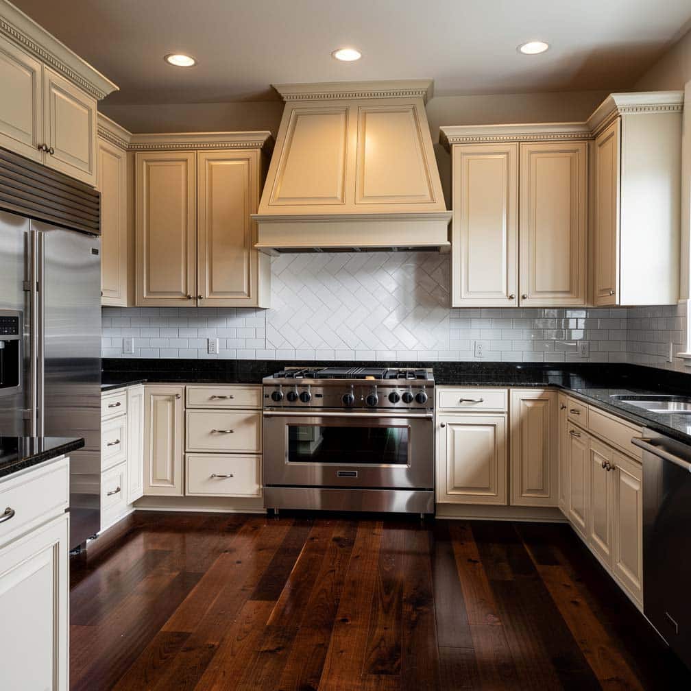 Off-white raised panel cabinets with rich dark maple wood floors and a diagonal subway tile backsplash