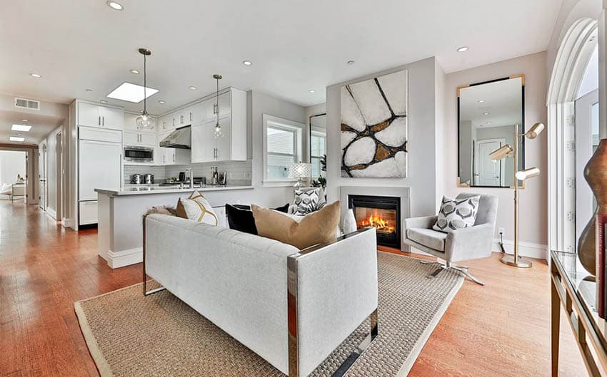 Open concept living room with fireplace and white cabinet kitchen