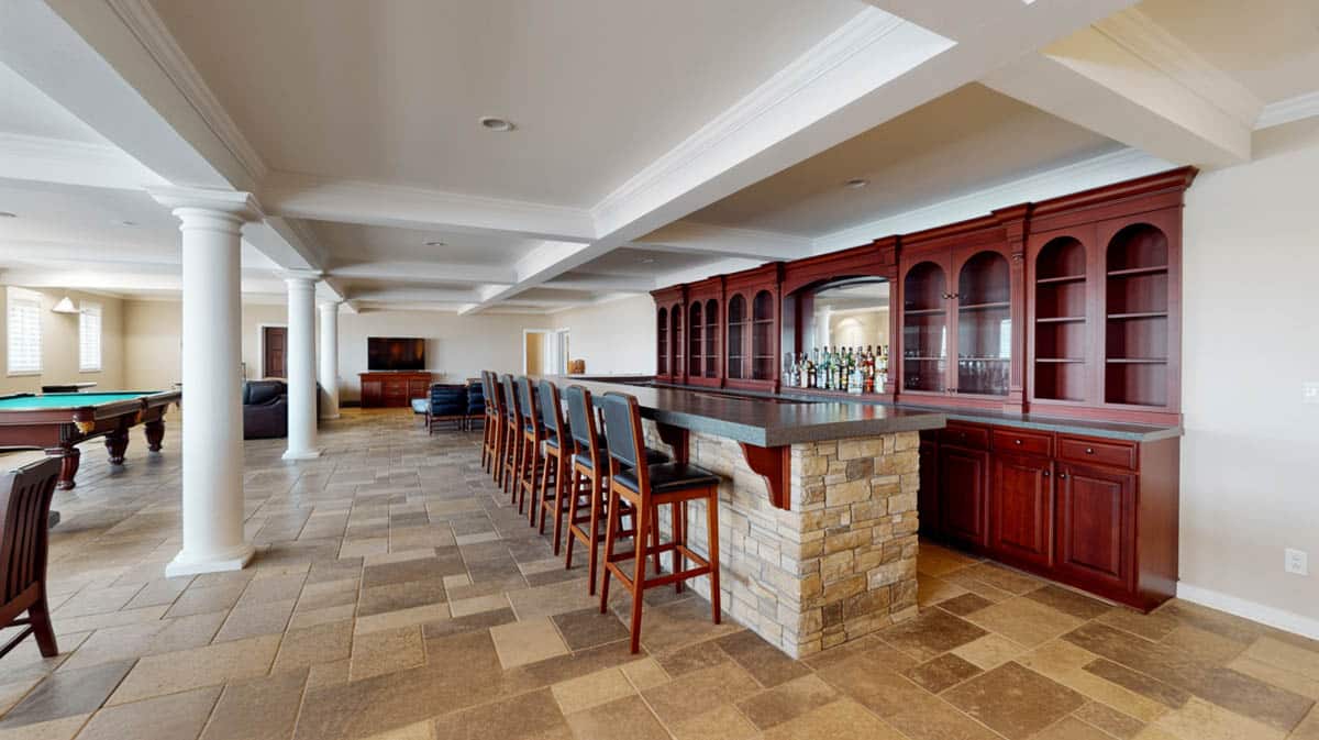 Bar with tan travertine floor tiles, stacked stone island walls, and dark wood cabinetry
