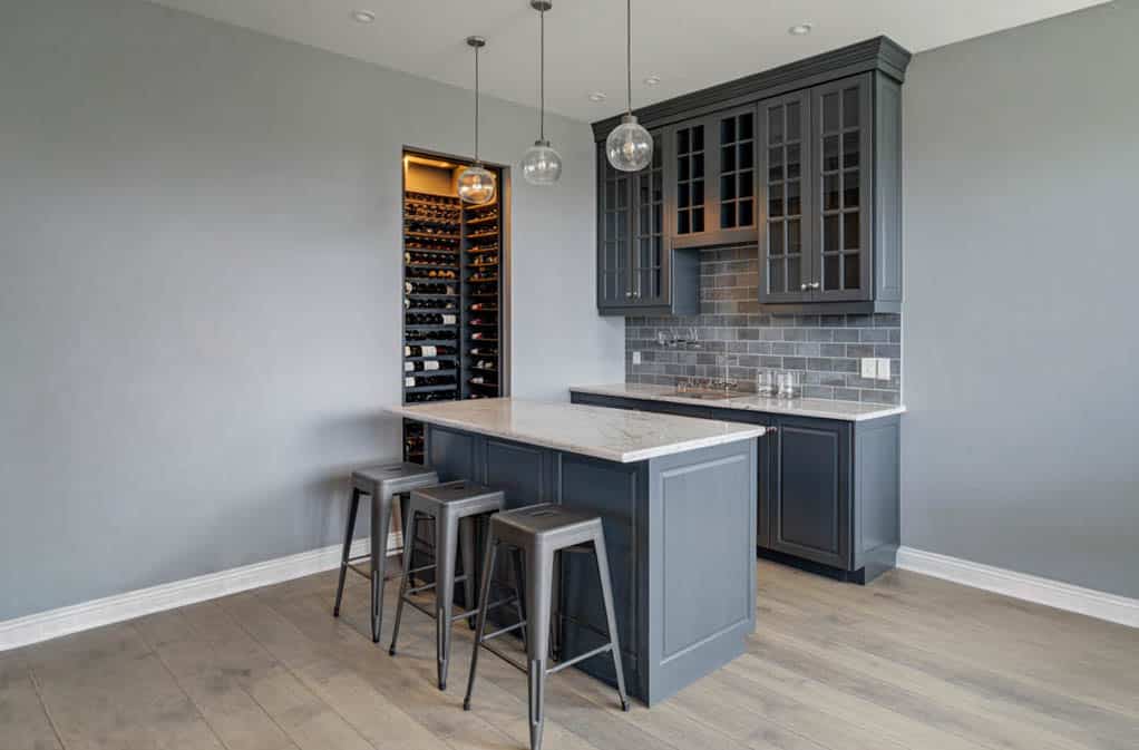 Bar space with cool gray walls, distressed floors, and a white stone countertop