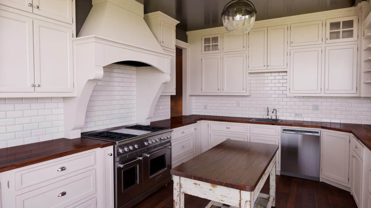 Farmhouse kitchen with white shaker cabinets, dark walnut butcher block countertop, arched range hood, and white subway tile backsplash