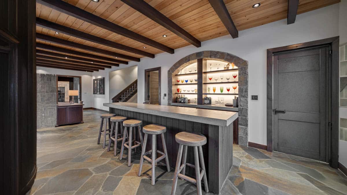 Rustic wood bar with ship-inspired plank ceiling, stone walls, and round wooden stools