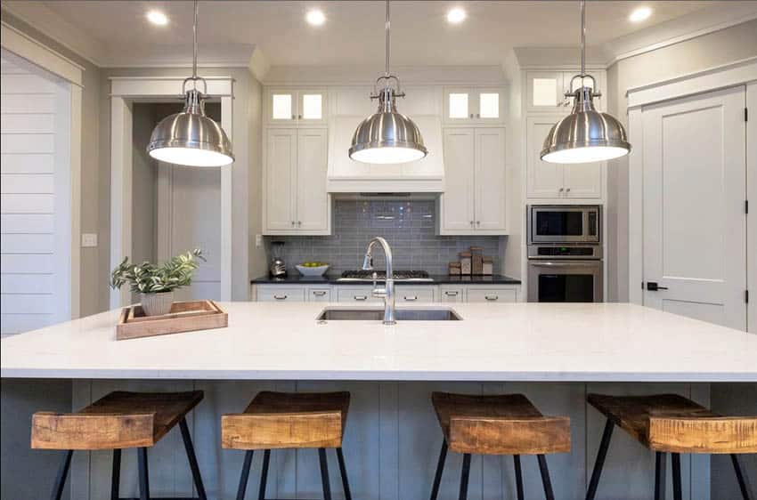 Contemporary kitchen with chrome pendant lights, white cabinets and blue island with quartz countertop