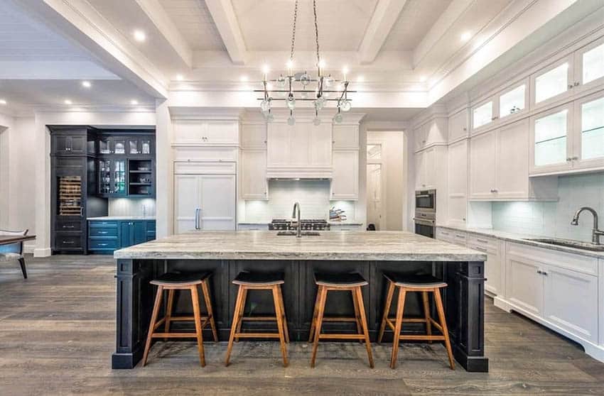 Contrasting kitchen island with black base cabinet and white main cabinets with beige granite countertops