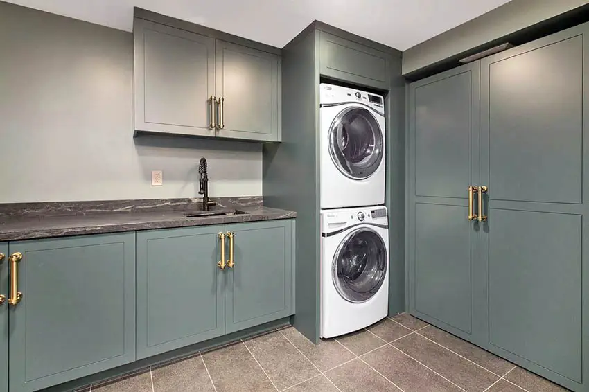 Custom laundry with green cabinets, quartz countertop and sink