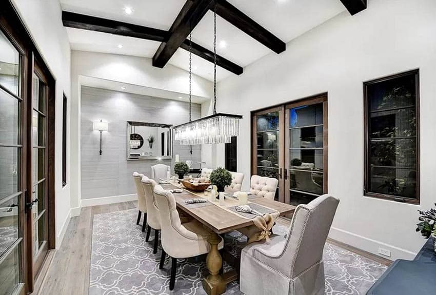 Dining room with linear chandelier, recessed fixtures, wall lighting and gray accent wall