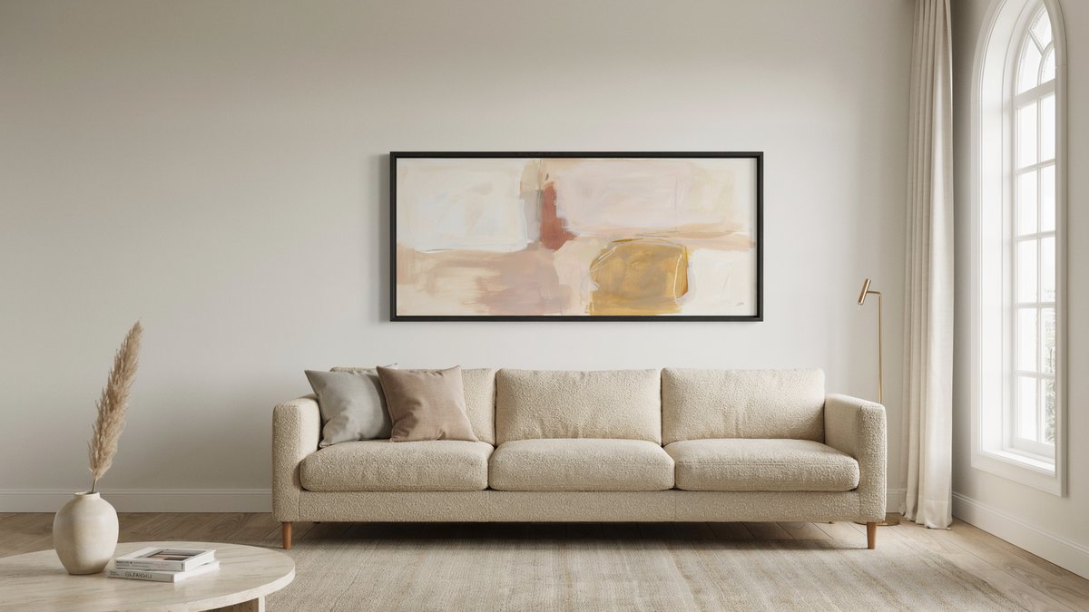 Wide horizontal painting hung just above a cream boucle sofa near an arched window