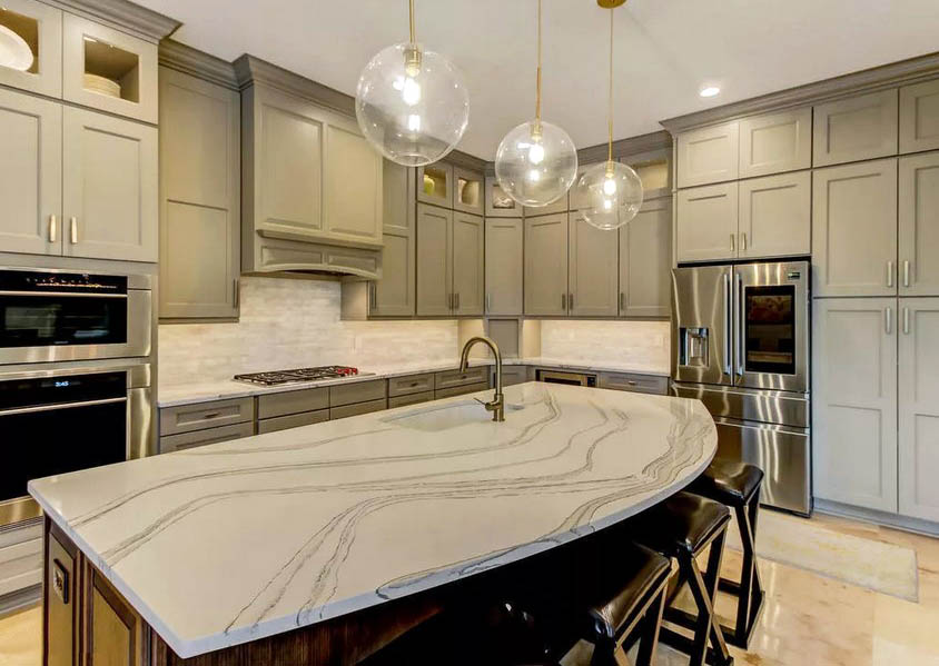 Kitchen with circular island with quartz countertop and light green cabinets