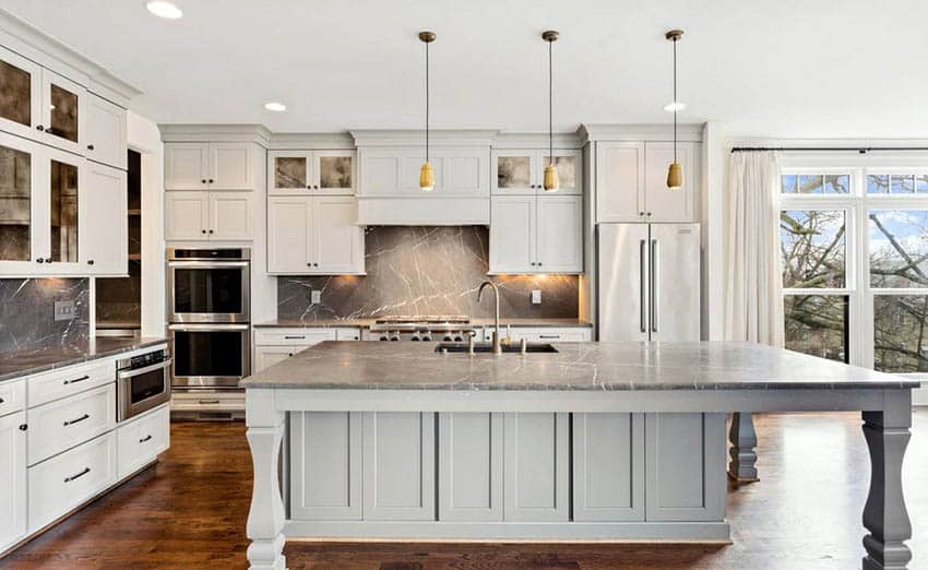 Kitchen with full function island with sink and soapstone countertops and white shaker cabinets