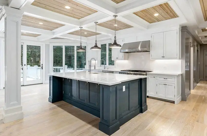 Kitchen with tongue and groove wood flooring and coffered ceiling with white cabinets and marble countertops