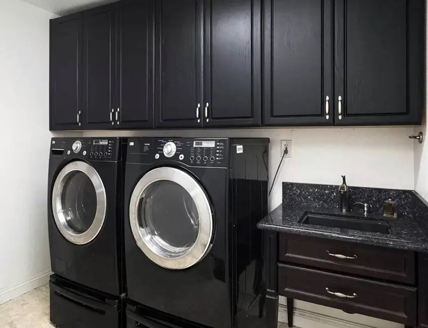 Front load washer dryer with black cabinets and sink vanity