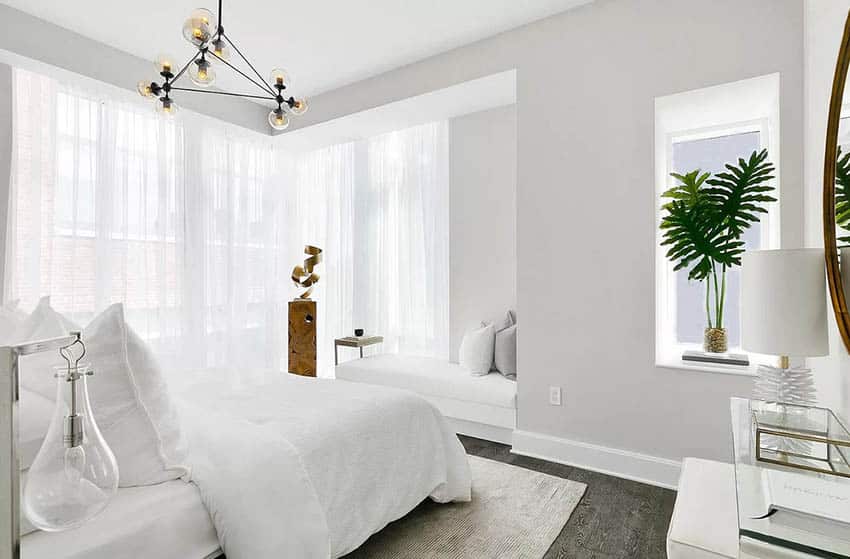 Master bedroom with wall niche, plant, window seat and modern chandelier