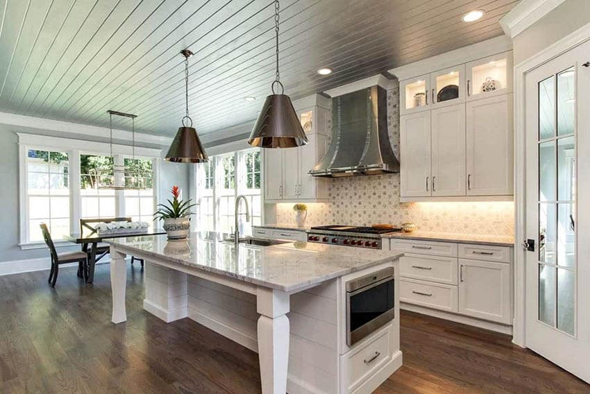 Open concept kitchen with under cabinet lights, white cabinets and island with legs