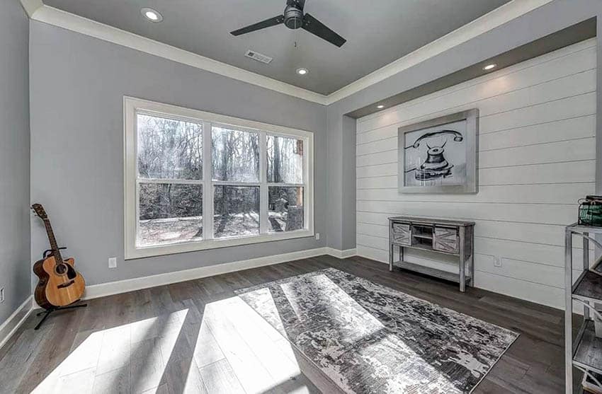 Room with indented wall with shiplap recessed lights and artwork