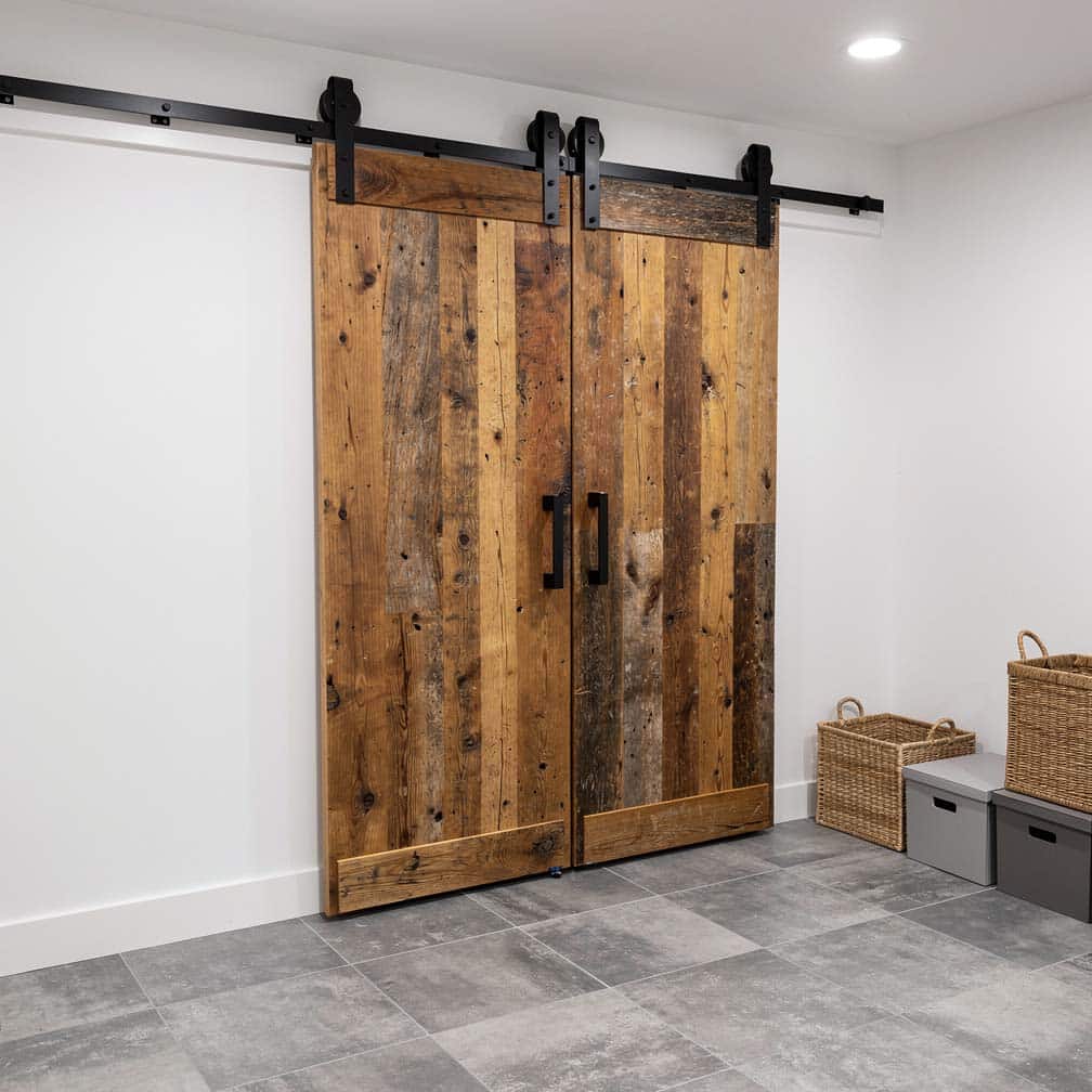 Basement laundry room with sliding reclaimed wood barn door hiding washer and dryer