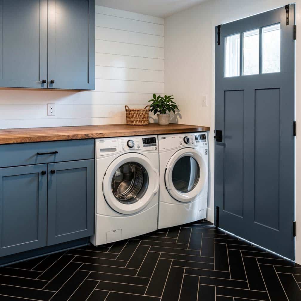 Custom basement laundry with steel blue cabinets, chevron tile floor, and Dutch door