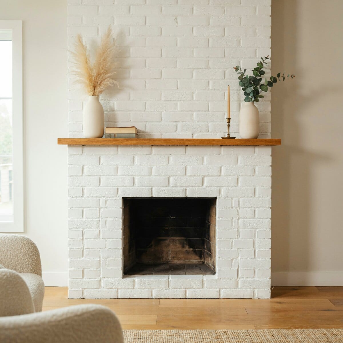 Freshly whitewashed white brick fireplace with a wood mantel and pampas grass