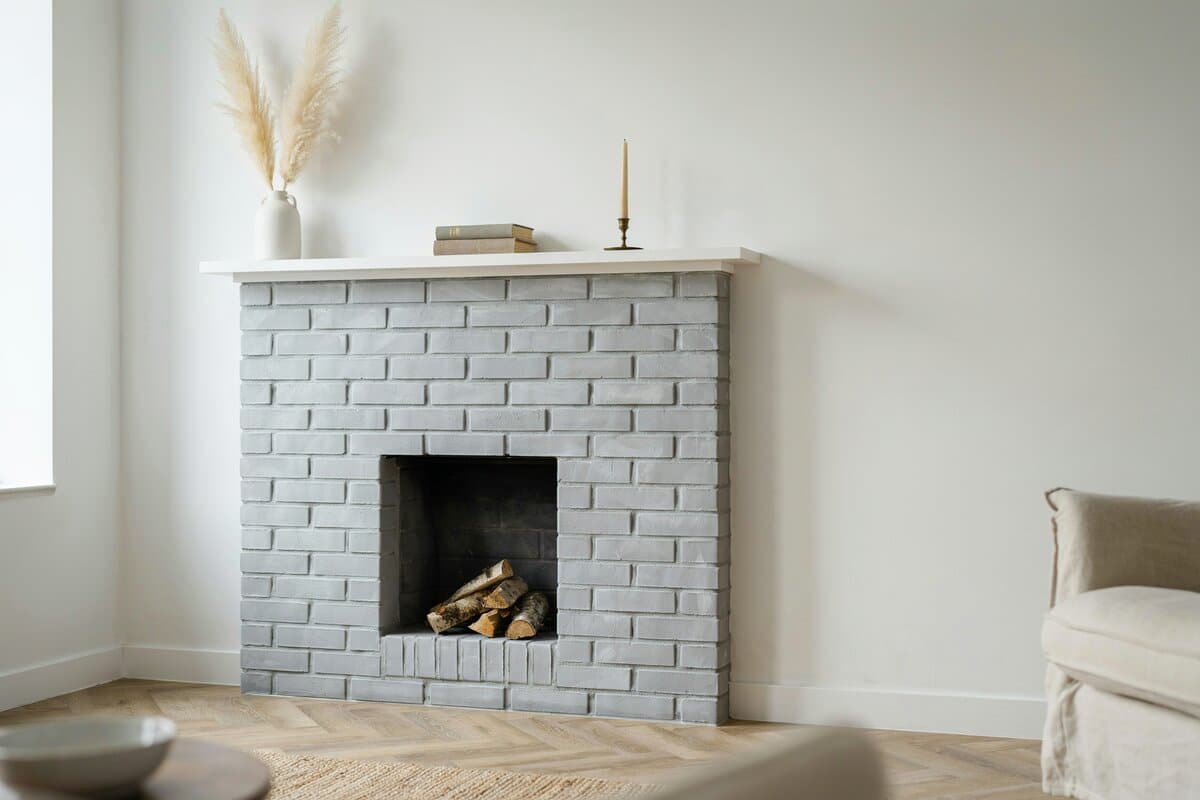 Graywashed brick corner fireplace against white walls with pampas grass decor