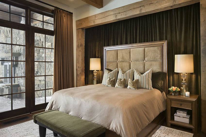 Country master bedroom with copper curtains wood beams over bed and dark wood french doors