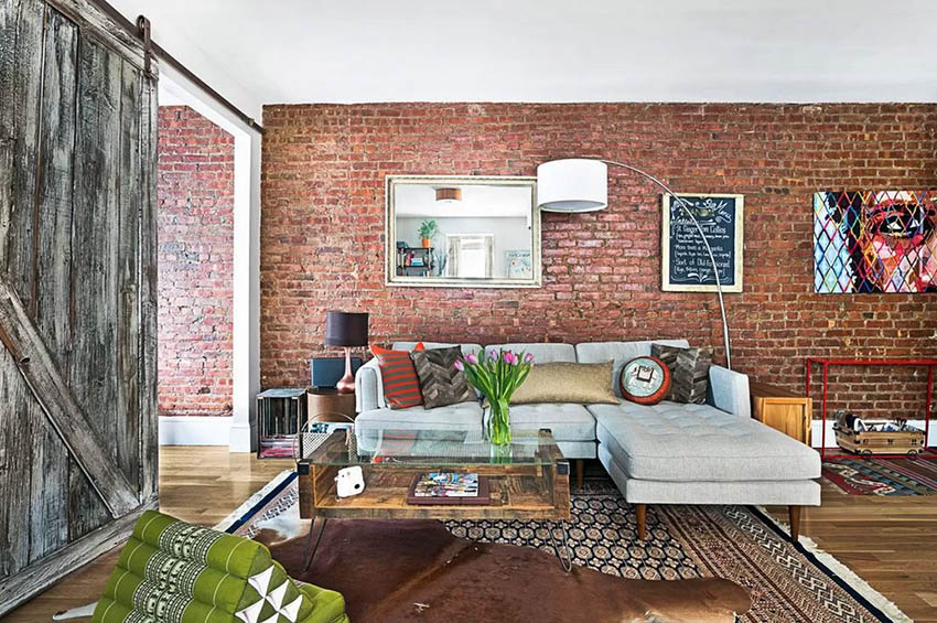 Exposed red brick wall living room with sliding barn door wood flooring