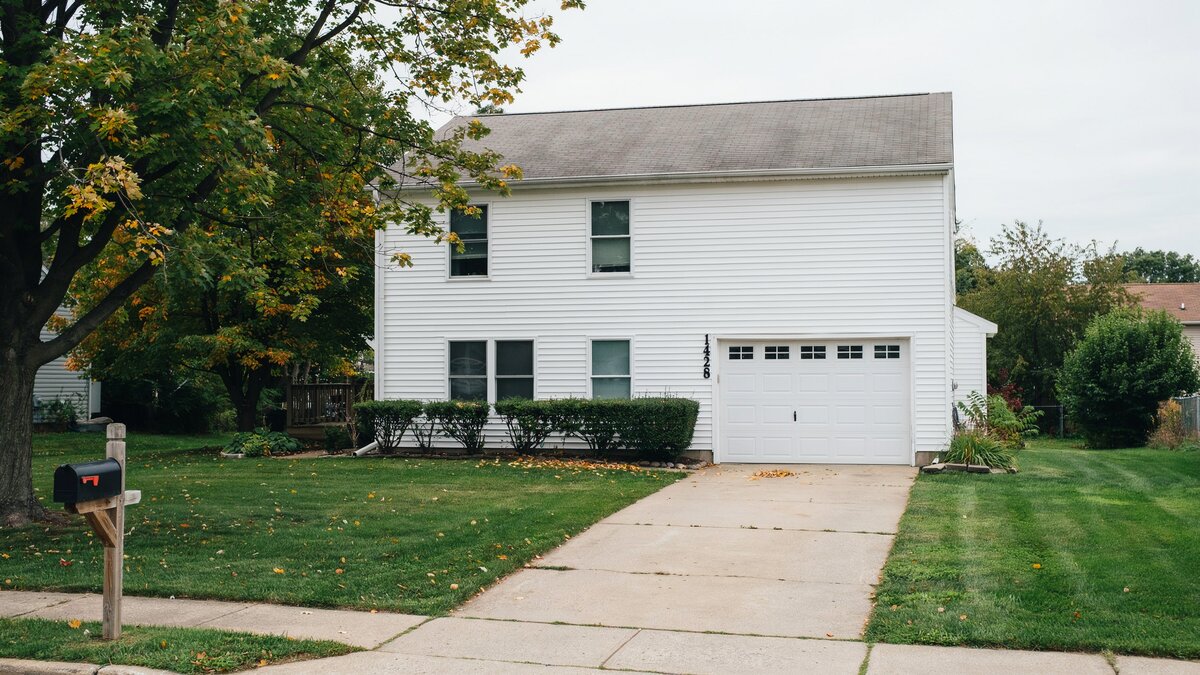 Suburban house with one white single bay door and a narrow driveway