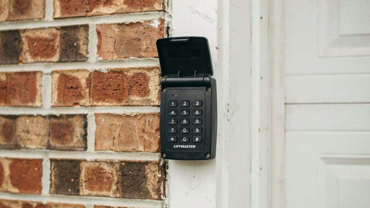 Numbered keyless entry keypad mounted on brick trim beside the door