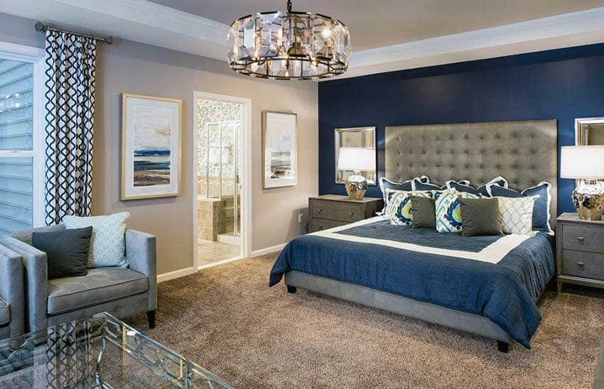 Gray tufted headbaord, blue comforter and printed curtains with drum chandelier