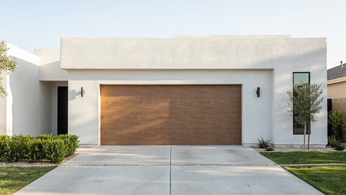 Two flush walnut slat wood doors set into a white stucco facade