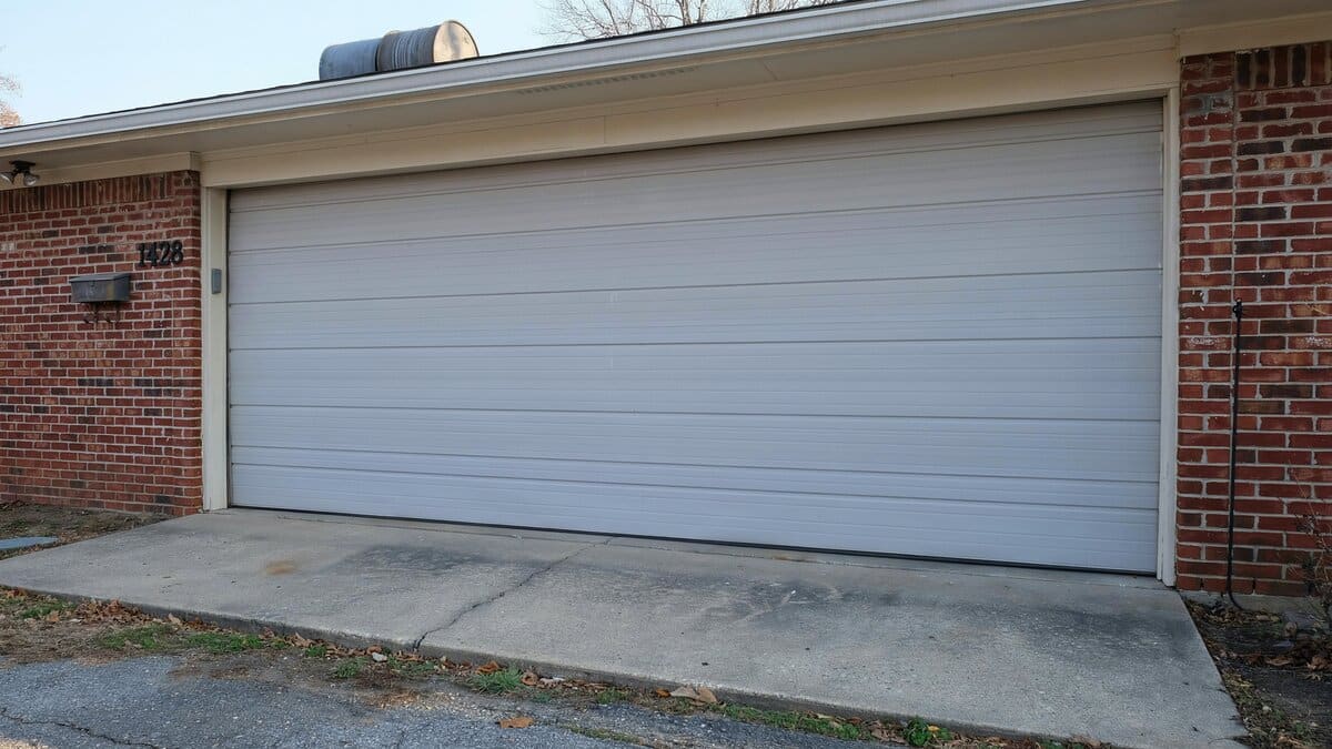Light gray roll up door built from narrow steel slats above a brick wall