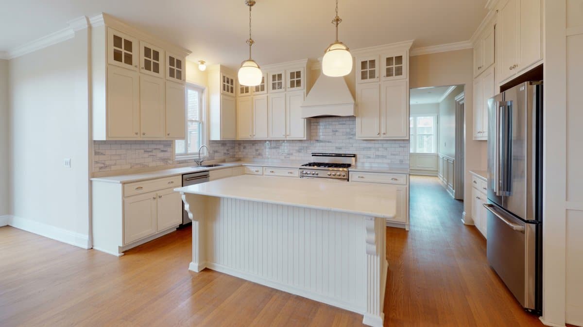 Classic white shaker kitchen with horizontal beadboard island paneling, globe pendant lights, and bright hallway