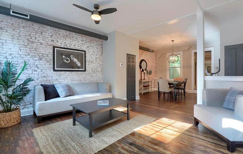 Whitewashed brick accent wall in living room with wood floors